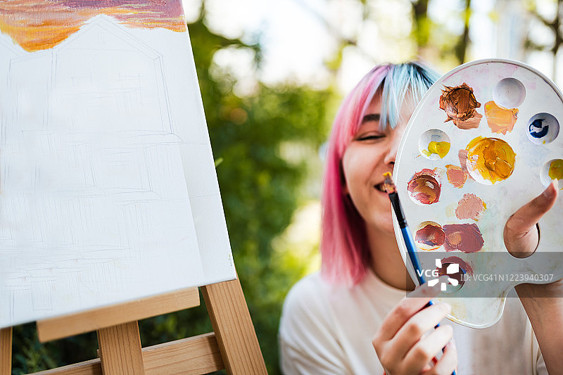 年轻漂亮的女子在画布上绘画图片素材