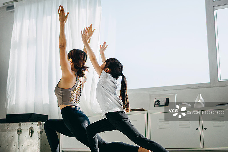 快乐的亚洲年轻母亲和女儿在家一起做瑜伽图片素材