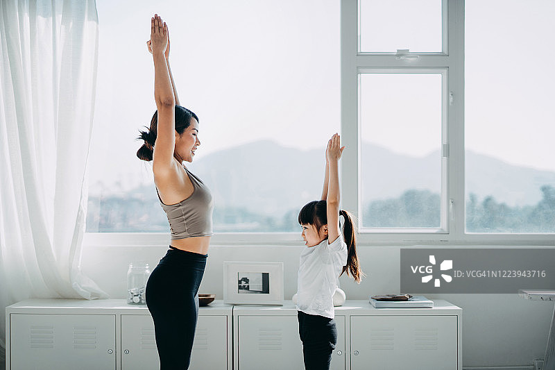 快乐的亚洲年轻母亲和女儿在家一起做瑜伽图片素材