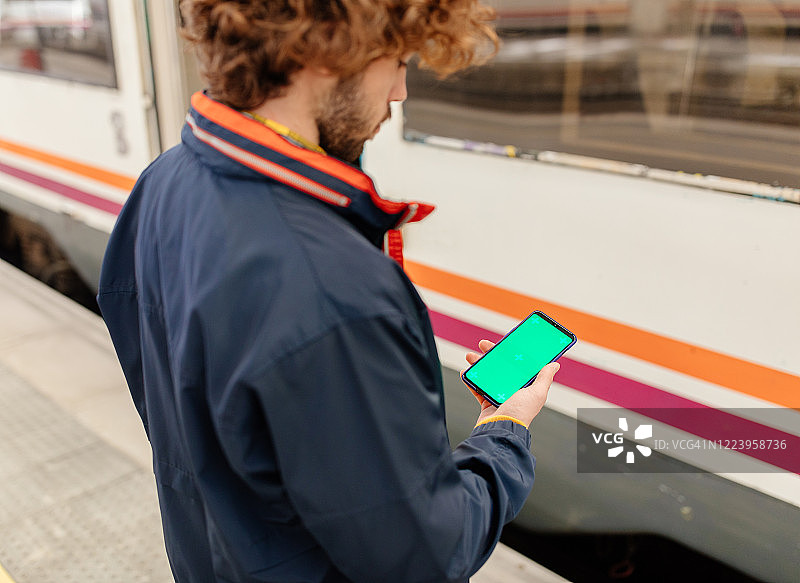 男子在火车站使用带绿屏的智能手机图片素材