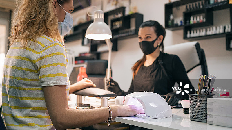 UV灯照凝胶美甲过程：美甲师为顾客涂指甲油图片素材