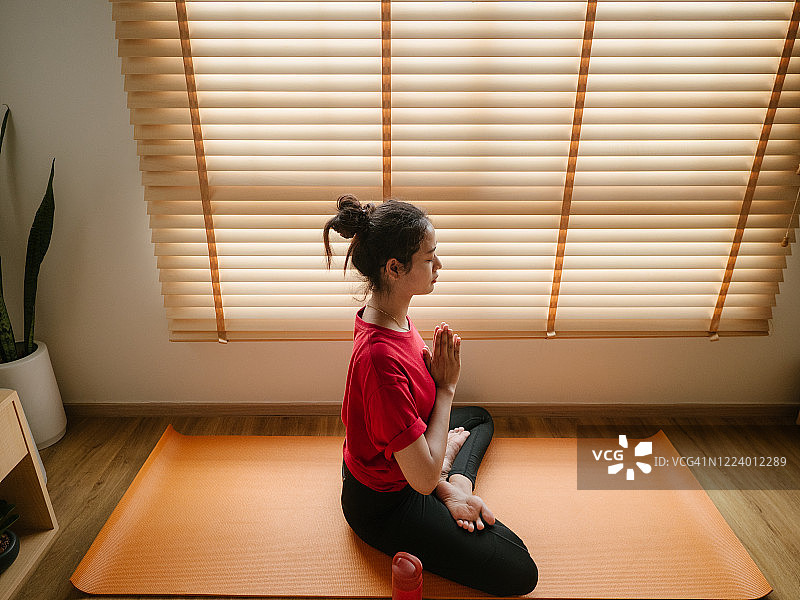 健康的女士在房间里做瑜伽锻炼。健身女人在家锻炼。图片素材