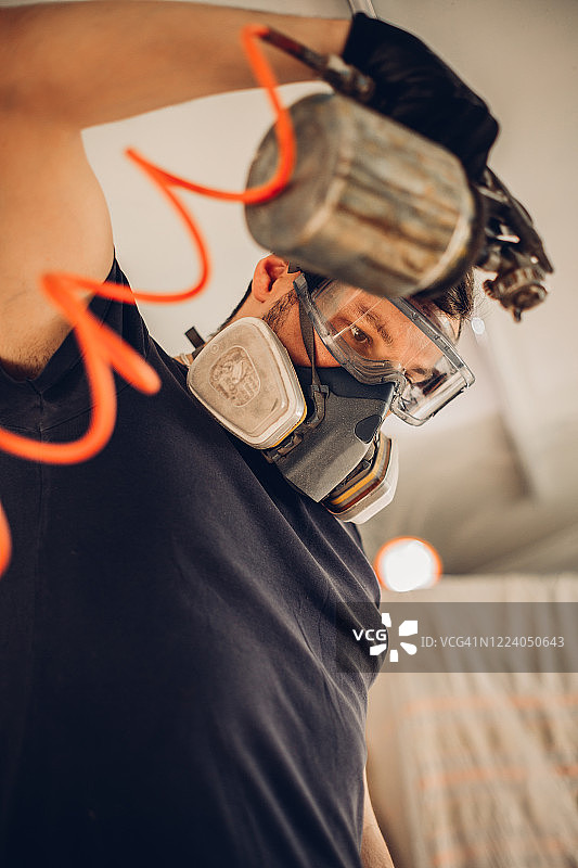 戴呼吸器面罩的男人粉刷木板图片素材