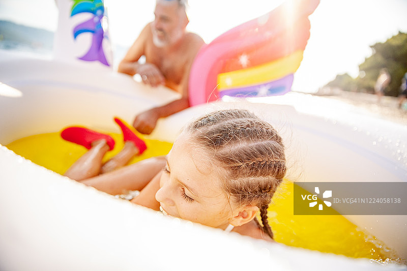 和父亲在泳池筏上享受暑假的女孩图片素材