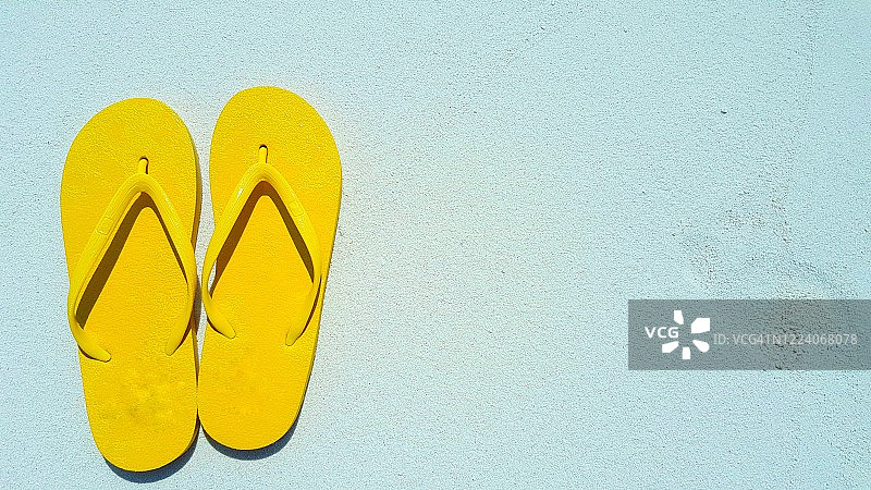 沙滩上遗留的黄色人字拖，留白区域，夏季旅行概念图片素材