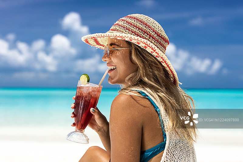 在海滩上喝鸡尾酒的年轻快乐女人图片素材