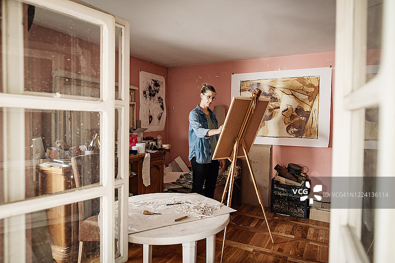 透过窗户看到艺术家正在绘画图片素材