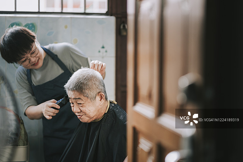 中国中年女性因旅行禁令在厨房为父亲理发图片素材