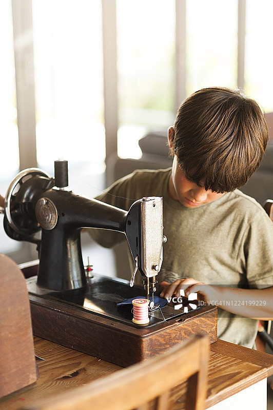 小男孩专心致志地使用缝纫机图片素材