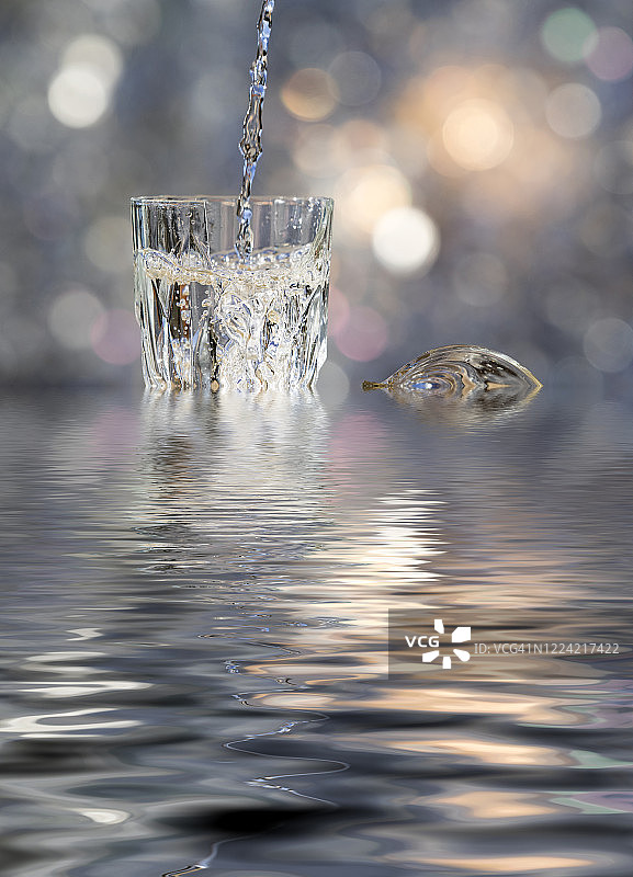 在户外，将水倒入一个破裂并倒映在水中的玻璃杯图片素材
