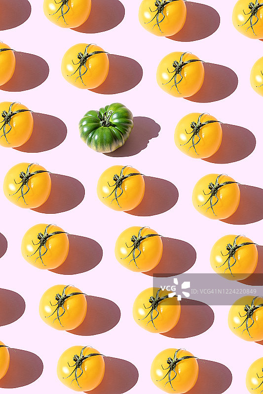 粉色背景上重复的黄色和绿色番茄图片素材