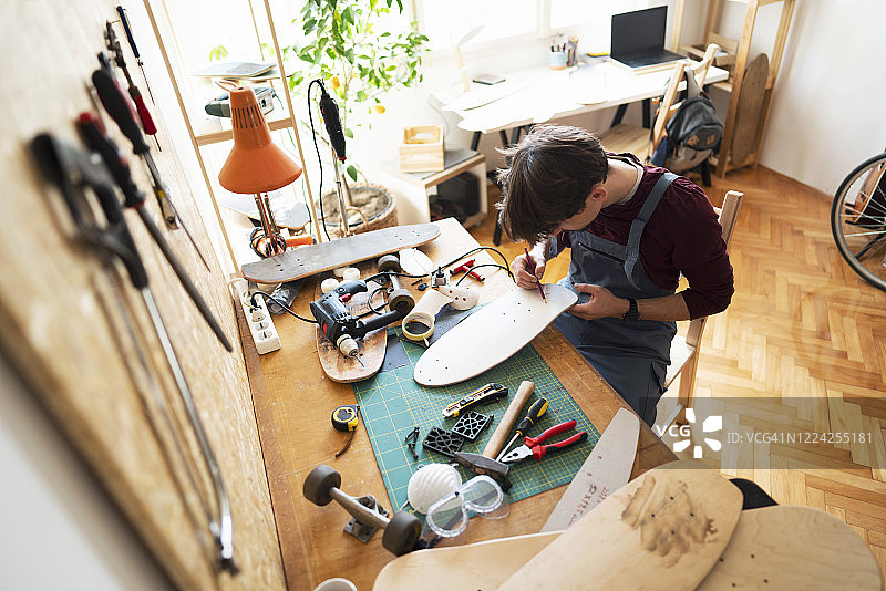 车间里的男子专注于他的新滑板创作图片素材