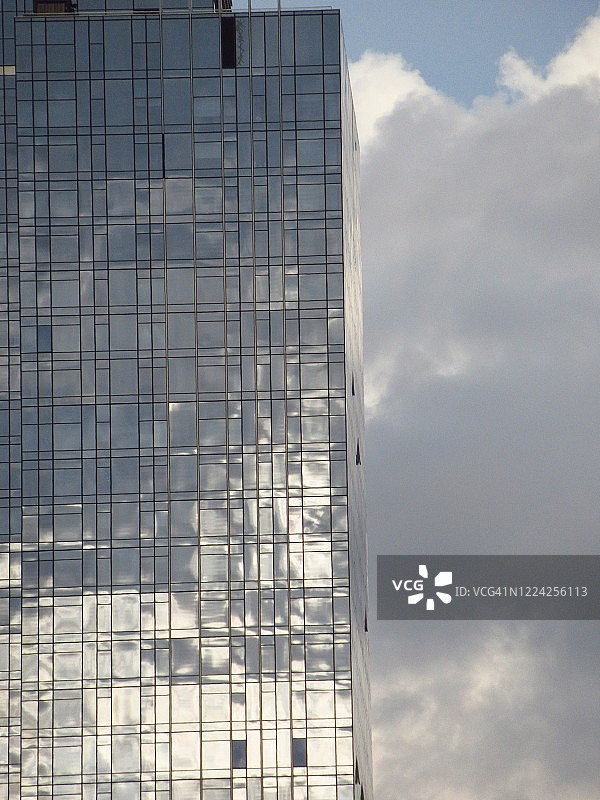 不断增长的云层背景下的现代金属玻璃摩天大楼特写图片素材