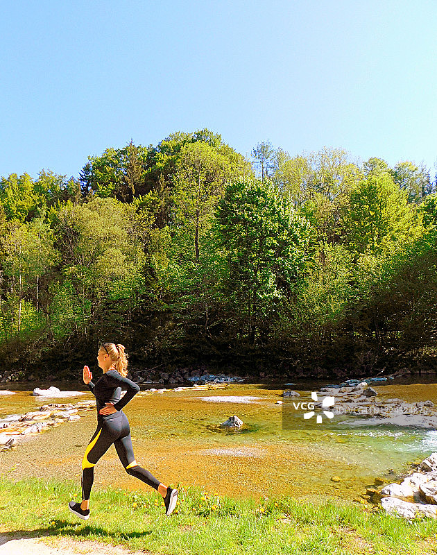在阳光下奔跑在公园里的金发女人图片素材