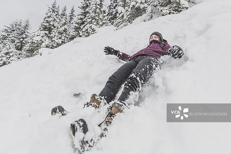 戴帽子的年轻女人在雪地里快速滑下，表情滑稽图片素材