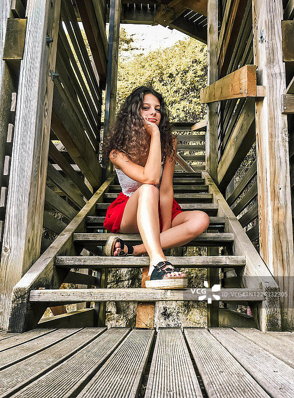 仰视：坐在楼梯上的沉思女孩图片素材