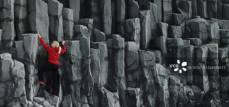 在冰岛南部攀登玄武岩柱的女人图片素材