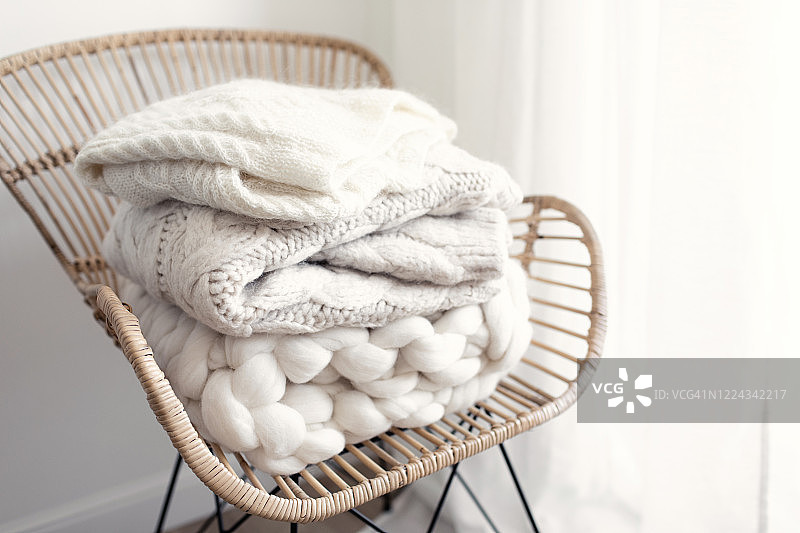 柳条扶手椅上堆放着舒适的羊毛白色针织毛衣图片素材