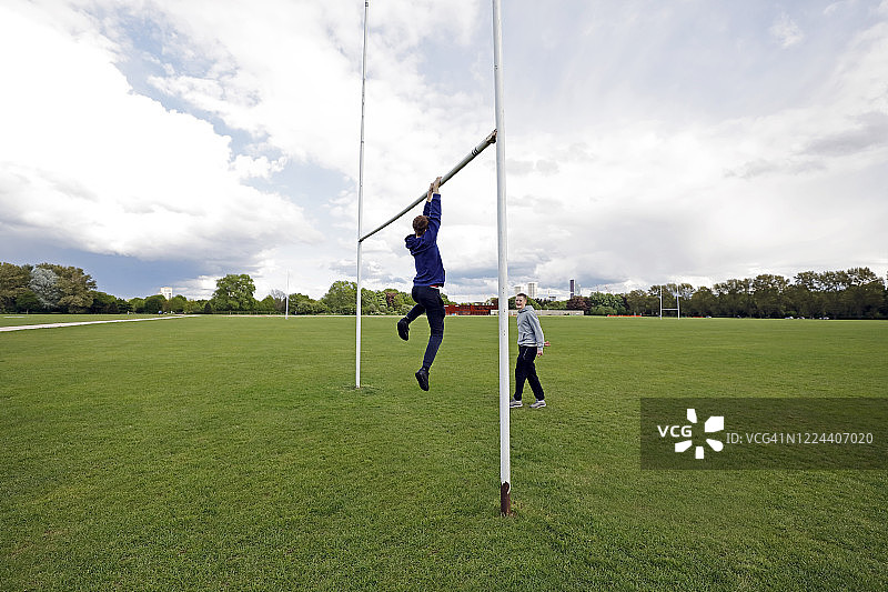 少年在橄榄球球门横梁上玩耍图片素材
