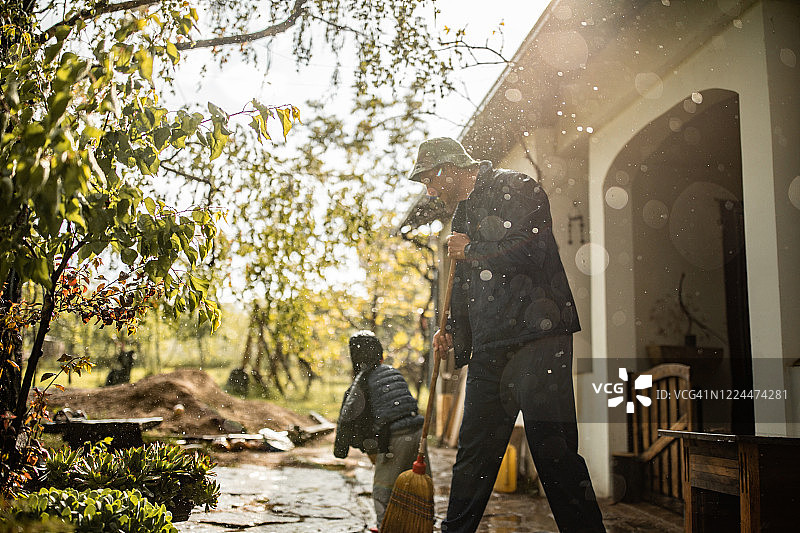 下雨天，父子俩清扫前院的积水图片素材