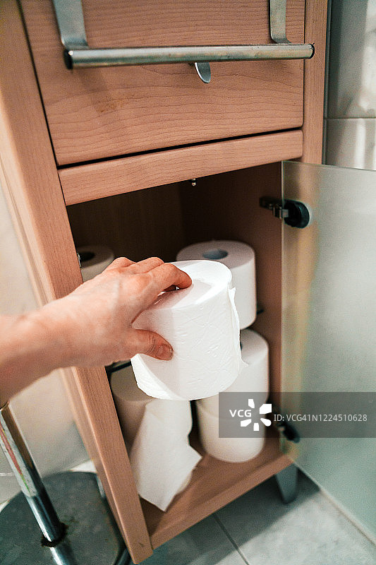 手将卫生纸放在浴室柜上图片素材