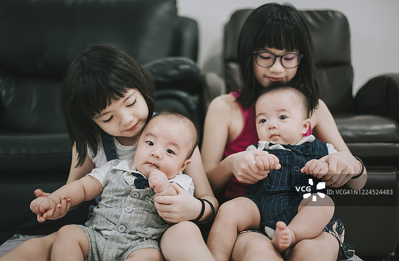 中国姐妹在客厅照顾她们的双胞胎男婴弟弟图片素材