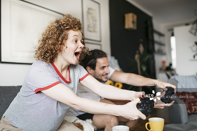一对年轻夫妇玩电子游戏的侧面视角图片素材