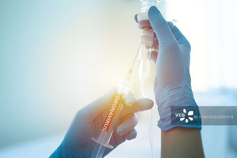 戴着外科手套的医生或护士手持新冠疫苗，准备进行疫苗接种（红色背景）图片素材