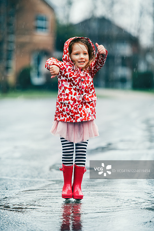 4岁小女孩在水坑里跳跃图片素材