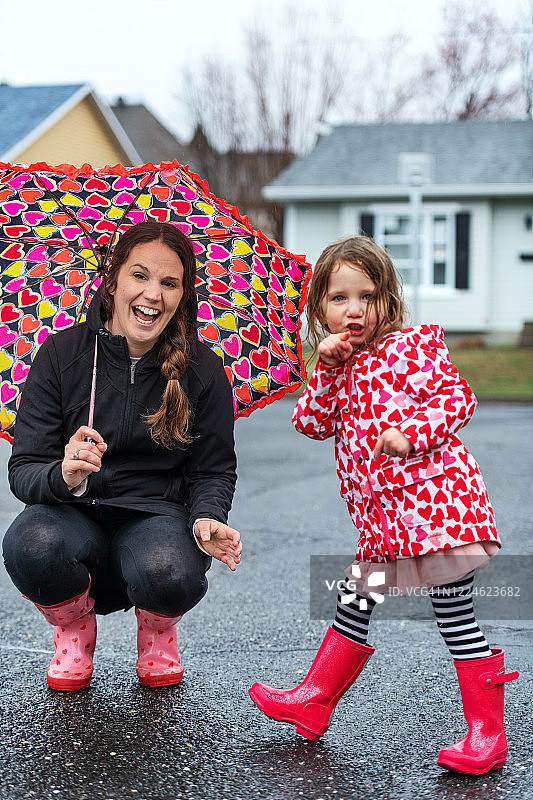 4岁小女孩在水坑里跳跃图片素材