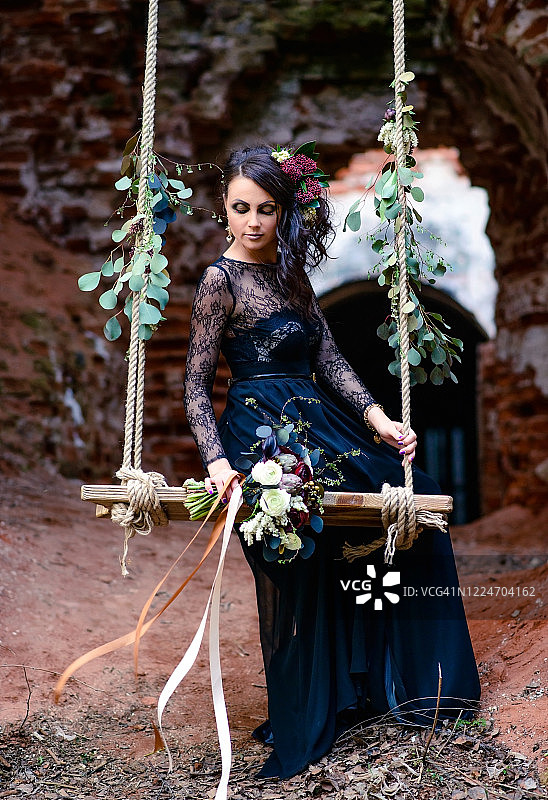 黑色连衣裙女子与鲜花、废墟和秋千图片素材