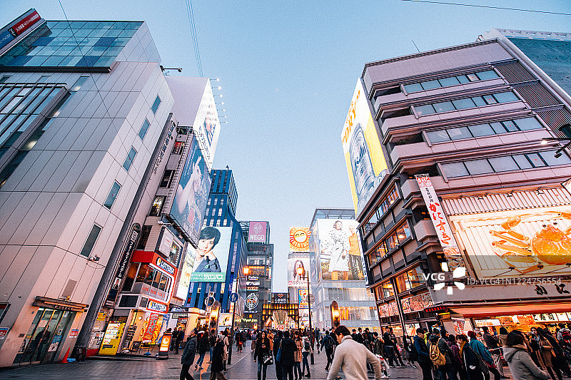 在日本大阪的道顿堀，五颜六色的广告牌照亮了大阪夜市周围的商店和零售店图片素材