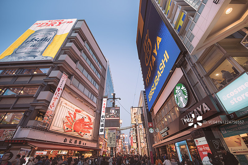在日本大阪的道顿堀，五颜六色的广告牌照亮了大阪夜市周围的商店和零售店图片素材