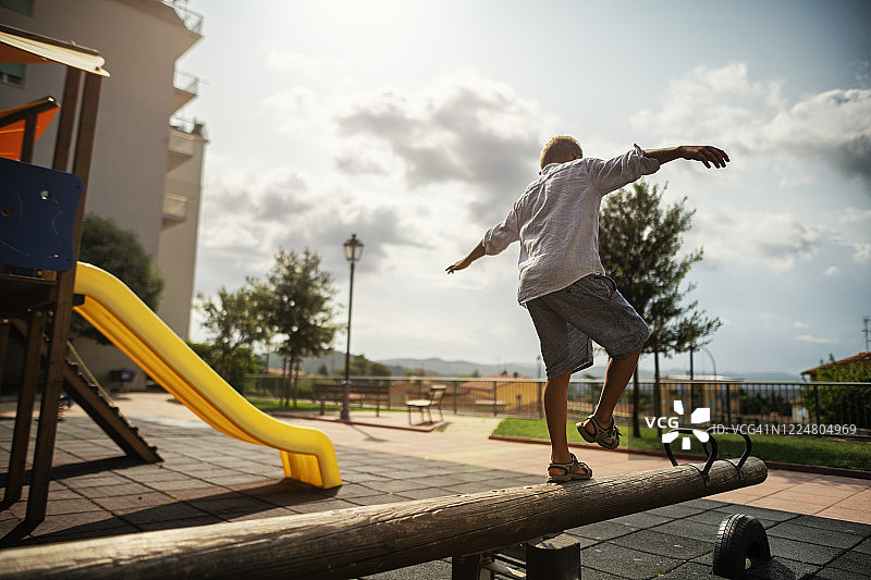 小男孩在跷跷板上保持平衡图片素材