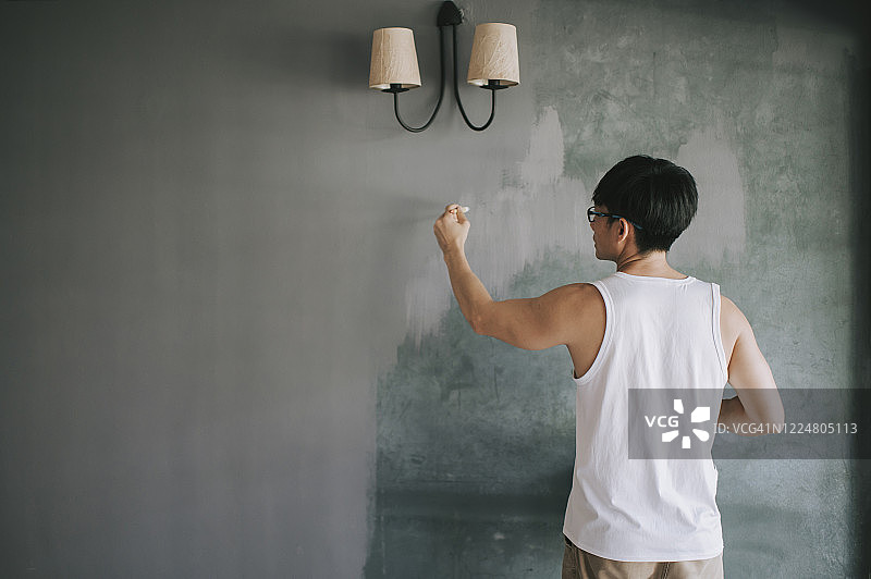 中国男子粉刷客厅墙壁图片素材