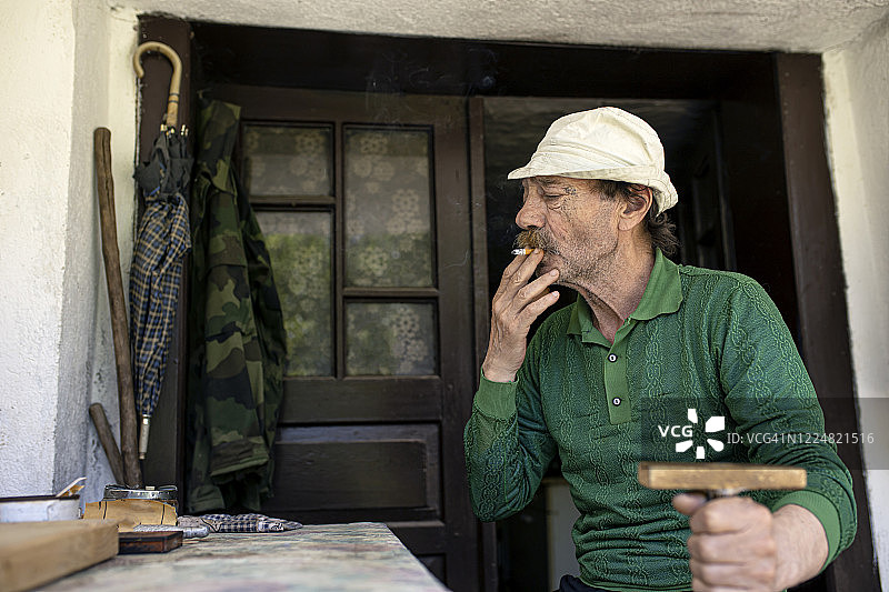 年长的男人在门廊上吸烟图片素材