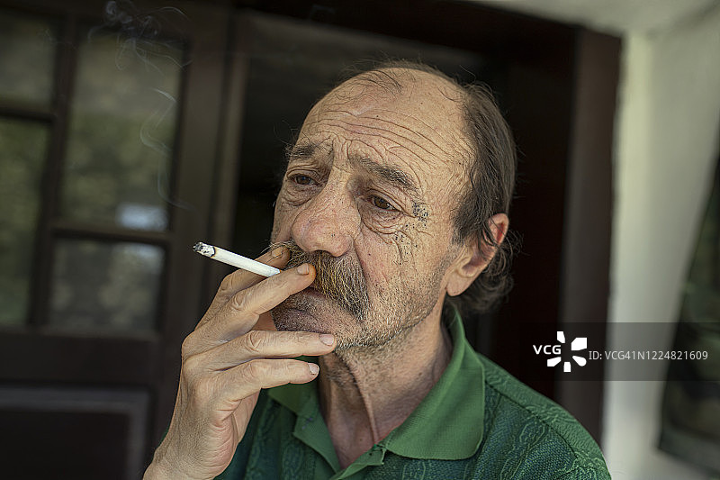 在门廊上吸烟的年长男人图片素材