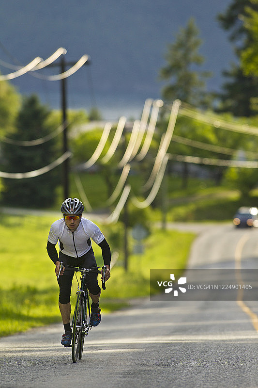 公路自行车骑行者与驶近的汽车图片素材