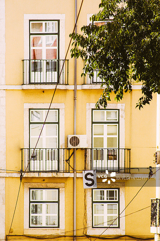 黄色建筑前的有轨电车电缆和交通标志图片素材