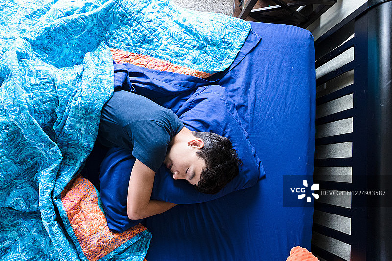 高角度视角：青少年男孩抱着枕头睡觉图片素材