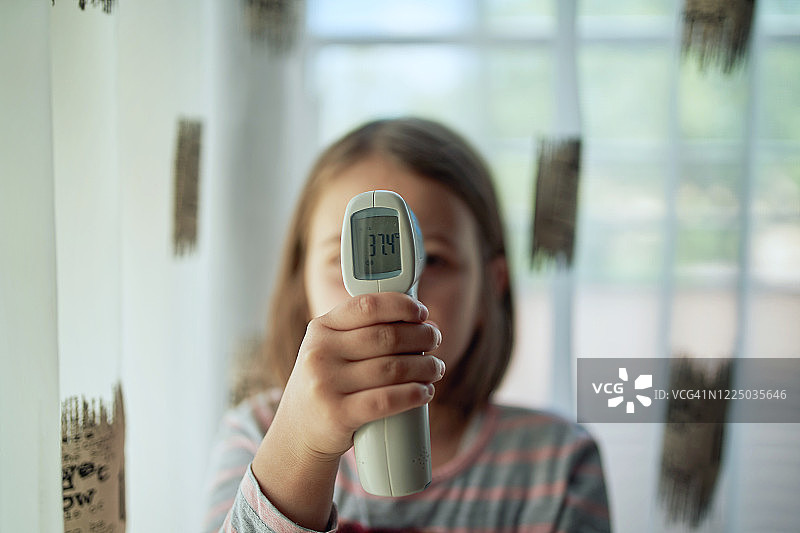 隔离期间快乐的女孩检查她的体温图片素材