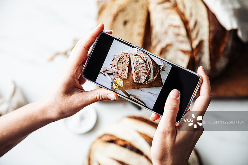女人拍摄新鲜的酸面包图片素材
