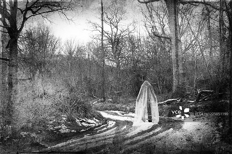 一个阴森恐怖的幽灵身影，站在一个阴森恐怖的森林中的轨道上，在一个寒冷的冬日，带有垃圾纹理编辑图片素材