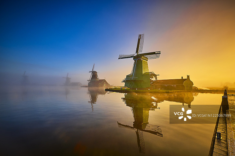 荷兰赞瑟斯汉斯运河沿岸日出时雾中的传统荷兰风车图片素材