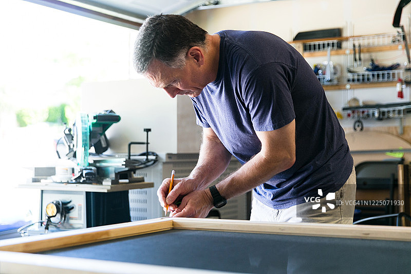年长的男人测量并标记木工项目图片素材