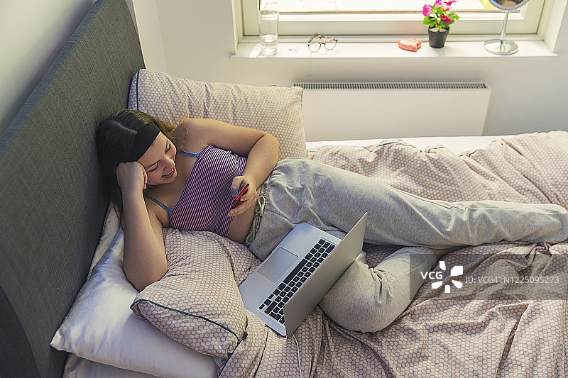 在卧室里使用智能手机的少女图片素材