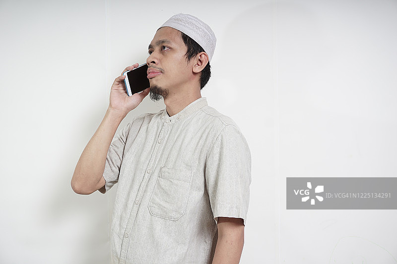 使用智能手机的亚洲穆斯林青年男子图片素材