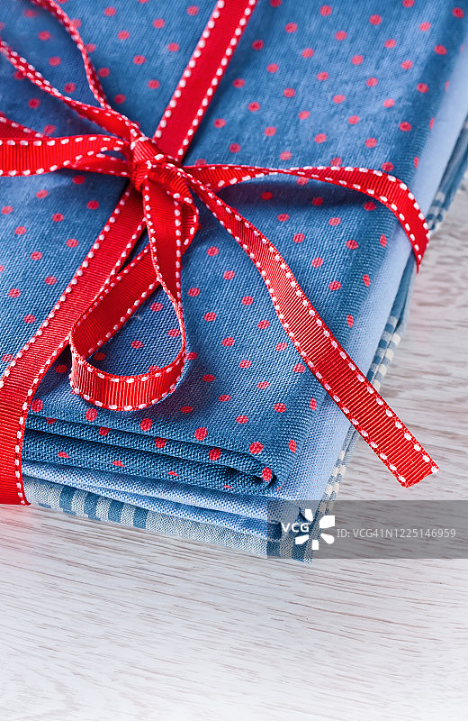 深蓝色红色圆点图案面料堆，桌面上的红色丝带图片素材