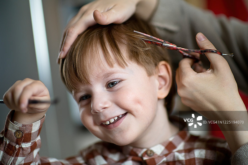 在家给孩子理发，孩子在玩玩具图片素材