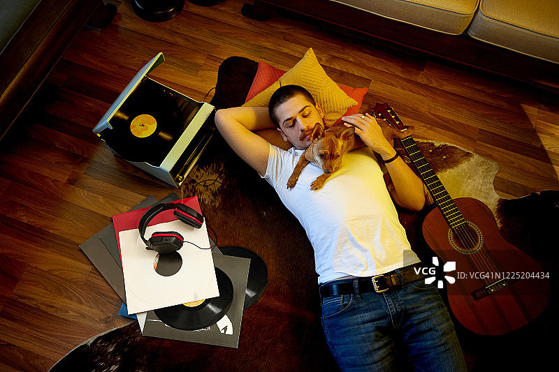 男人和他的狗在地板上听黑胶唱片图片素材